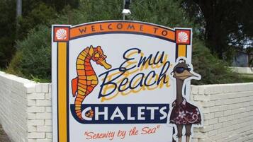 Cartel de bienvenida para los Chalets Emu Beach, con una ilustración de un caballito de mar y un avestruz.