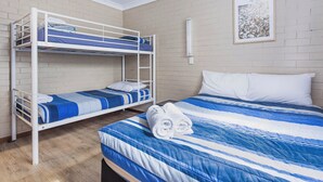 Una habitación con literas, una cama individual y un cuadro en la pared.