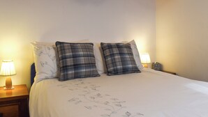 A bedroom with a wooden ceiling, two plaid pillows, a floral bedspread, and two bedside lamps. - 1 bedroom accommodation in Tatham, near Lancaster (Tatham, near Lancaster)