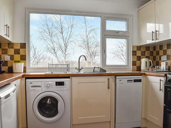 A compact kitchen with a washing machine, a dishwasher, and a coffee maker. - 2 bedroom accommodation in Minehead (Minehead)