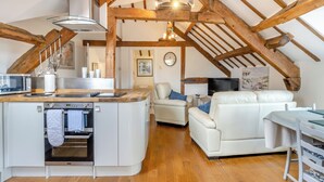 Een ruime loft met keuken, woongedeelte en eettafel.