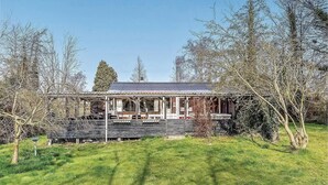 A rustic wooden house with a porch, surrounded by trees and grass. - Nice home in Sydals with WiFi (Sydals)