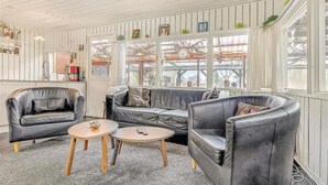 A conservatory with a leather sofa, two armchairs, and a small wooden table. - Nice home in Sydals with WiFi (Sydals)
