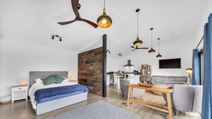 Een moderne slaapkamer met een houten accentmuur, een groot bed, een bureau en een zithoek.