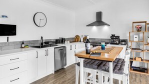 Een moderne keuken met witte kasten, een houten eettafel en een ingebouwd fornuis.
