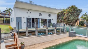 Een modern huis met zwembad, terras en decoratie in nautische stijl.