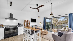 Een moderne keuken met een centraal eiland, witte kasten en een groot raam met uitzicht op de omgeving.