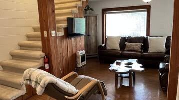 A living room with a wooden staircase, a rocking chair, a sofa, and a ceiling fan.