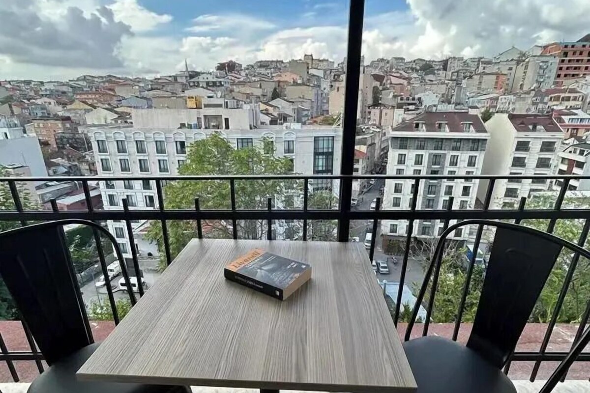 A balcony with a table and two chairs, overlooking a cityscape.