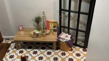 Una habitación con piso estampado, una mesa de madera con adornos, un cuadro enmarcado en la pared y una puerta con un panel de vidrio.