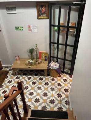 A room with a patterned floor, a wooden table with decorative items, a framed picture on the wall, and a door with a glass panel. - NarPera Taksim Boutique Hotel (Istanbul)