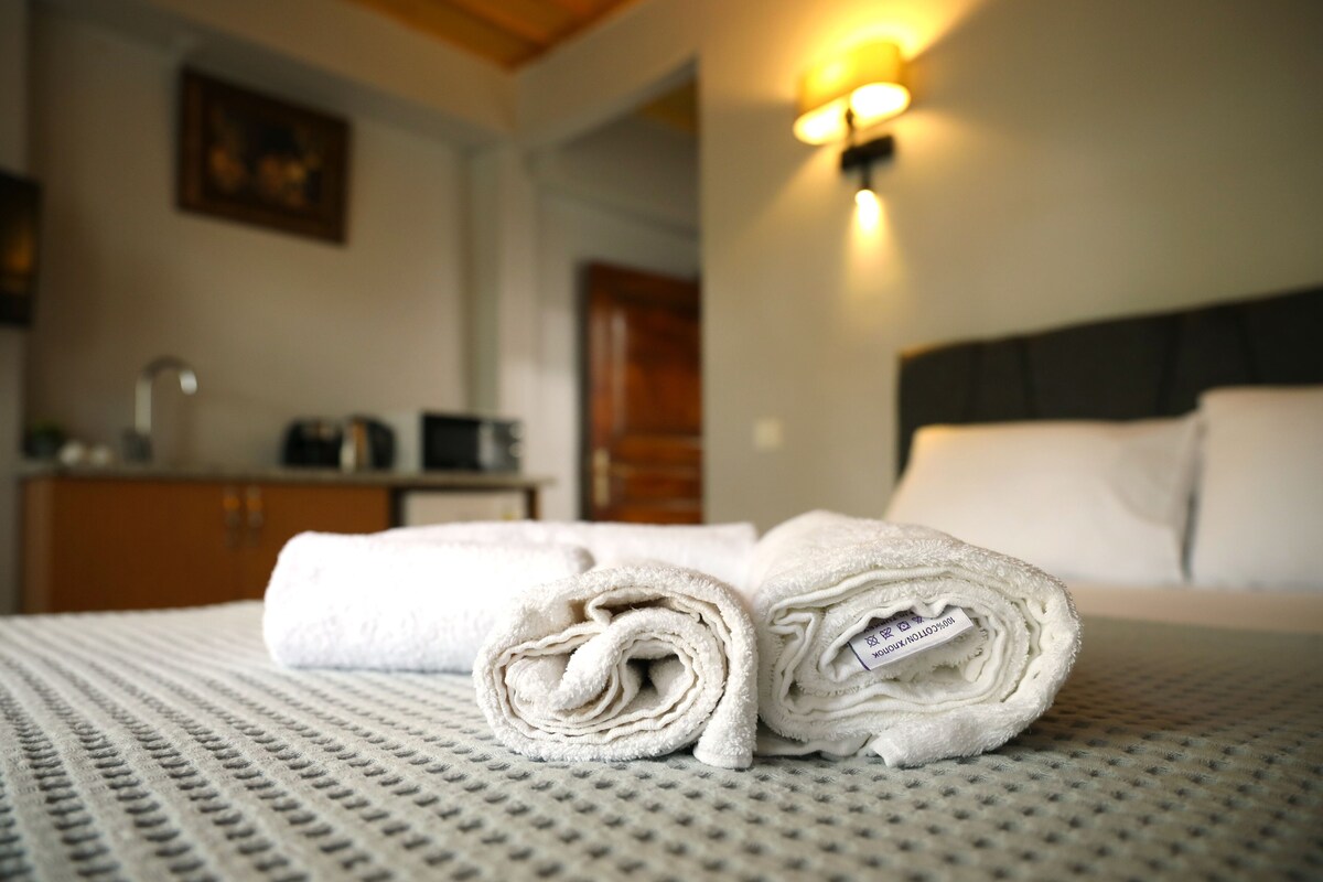 A neatly made bed with rolled white towels and a headboard.