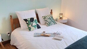 A neatly made bed with white bedding, a wooden headboard, and a bedside table with a lamp. - Gîte Philomène Dans Ancien Presbytère - 2 Pers - à St Georges de Lévéjac (Massegros Causses Gorges)
