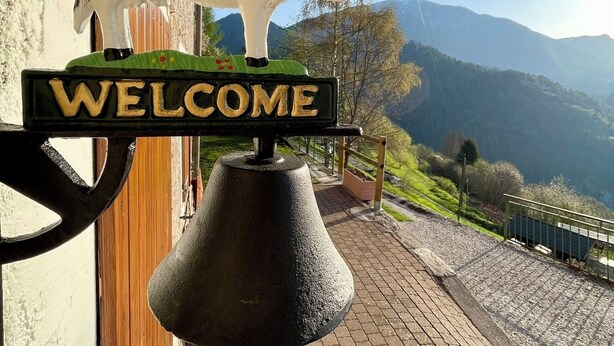 A bell with a cow decoration and a 'WELCOME' sign.