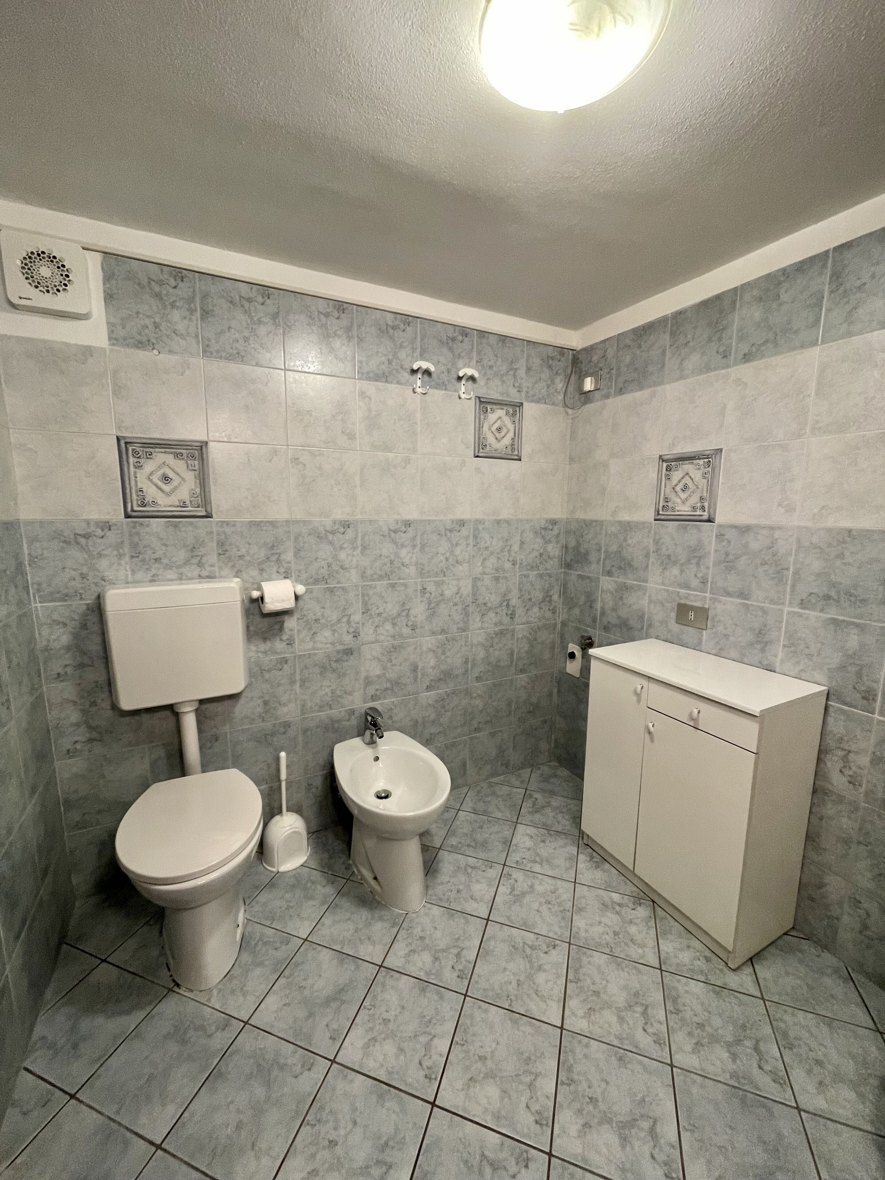 Et badeværelse med toilet, bidet og skab.