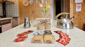 A kitchen counter with a coffee maker, a teapot, and various food items including bread and packaged snacks.