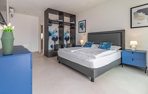 Une chambre à coucher moderne avec un grand lit, des tables de chevet et une armoire.