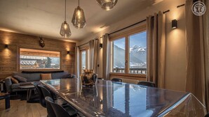 Un comedor moderno con una mesa de vidrio, paredes de madera y vistas a la montaña.