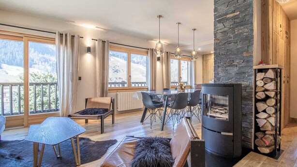 Una sala de estar moderna con chimenea, comedor y ventanas amplias con vistas a las montañas.