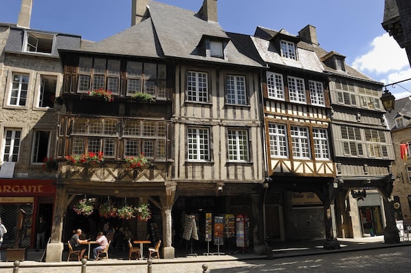 A traditional European building with multiple stories, timber framing, and a ground-floor shop with outdoor seating.