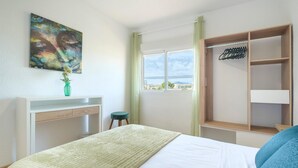 A bedroom with a bed, a desk, a chair, a wardrobe, a window with a view, and a painting on the wall. - Stunning apartment in El Campello with WiFi (El Campello)