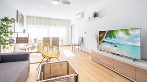 A modern living room with a flat-screen TV, a dining area with a table and chairs, and a large window with sheer curtains. - Stunning apartment in El Campello with WiFi (El Campello)