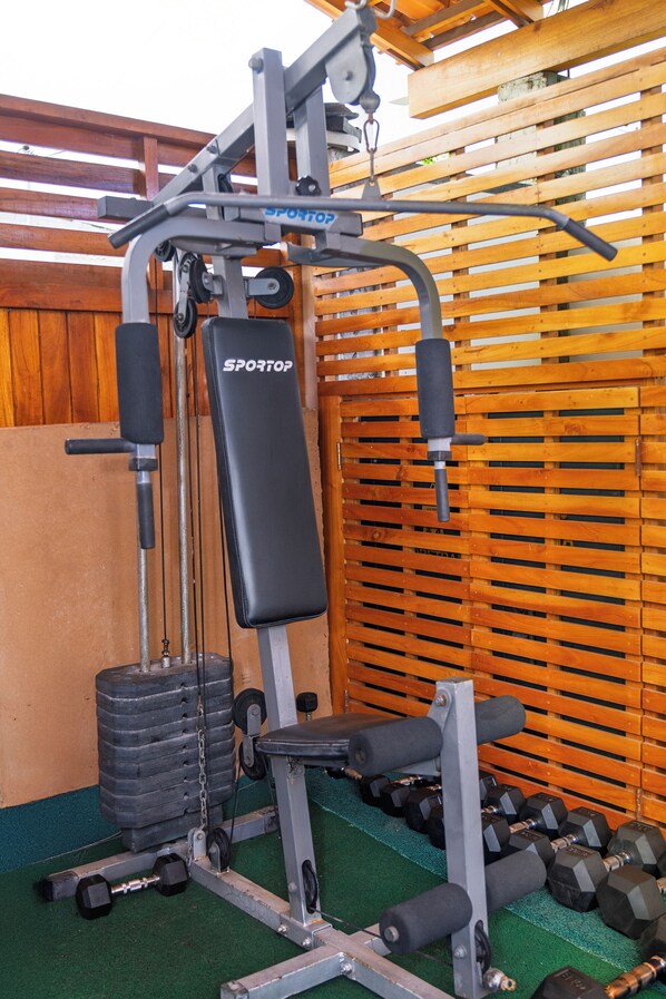 Une salle de sport équipée d’un banc de musculation, d’haltères et d’un support à squats.