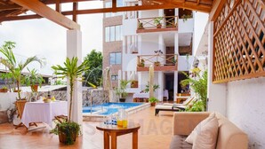 Un espace piscine comprenant des chaises longues, une table avec des boissons et des plantes en pot.