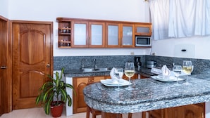 Une cuisine avec des meubles en bois, un plan de travail en granit, un four à micro-ondes et une table à manger dressée avec des assiettes et des verres.