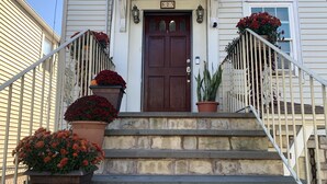 Une maison avec une porte d’entrée marron, le numéro 523, et un escalier en pierre menant à l’entrée.