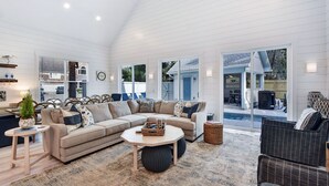 Ein geräumiges Wohnzimmer mit einer großen Eckcouch, einem runden Couchtisch und einem Essbereich mit Tisch und Stühlen.
