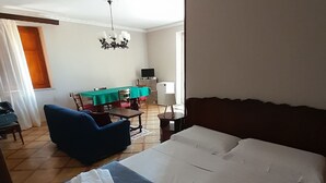 Een hotelkamer met een groot bed, een bureau met een computer, een eettafel met stoelen en een kroonluchter.