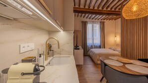 A compact hotel room with a kitchenette, a bed with a view, and a dining area. - Appartement de Charme Aix en Provence (Aix-en-Provence)