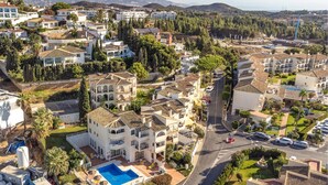 Zona residencial con edificios de varios pisos, una piscina y una calle con vehículos.