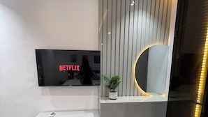 A modern living room with a flat-screen TV mounted on the wall displaying 'NETFLIX'. - Esporta Suites Hotel GRA (Lagos)