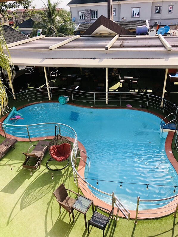 A swimming pool with lounge chairs and a covered seating area. - Esporta Suites Hotel GRA (Lagos)