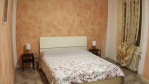Een slaapkamer met een bed, twee nachtkastjes, een raam met gordijnen.