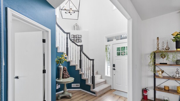 Un intérieur moderne avec un escalier, une porte blanche et une étagère ornée d’objets décoratifs.
