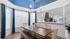 Un espace repas avec une table en bois, des bancs et des chaises blanches.