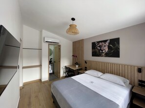A bedroom with a bed, a desk, a chair, a television, and a wall-mounted air conditioner. - Vita Hotel Boutique (Medellín)