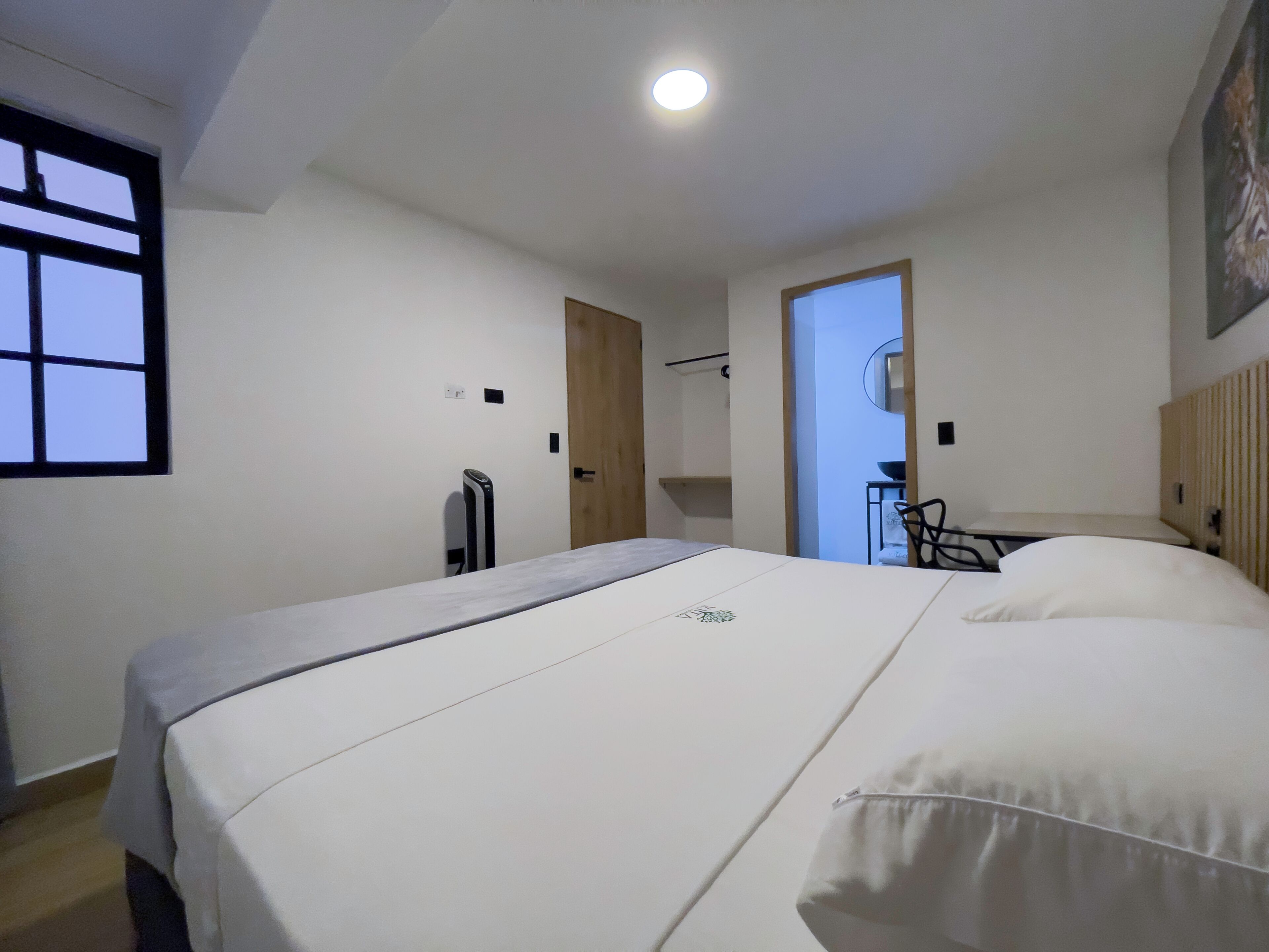 A bedroom with a bed, a desk, and a chair.