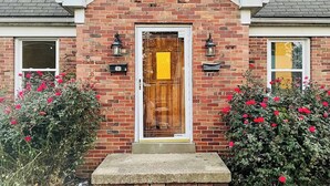 A brick house with a wooden front door, two black lantern-style lights, and a small concrete step leading to the door. - Cozy & Centrally Located APT - KING BED
 (Evansville)