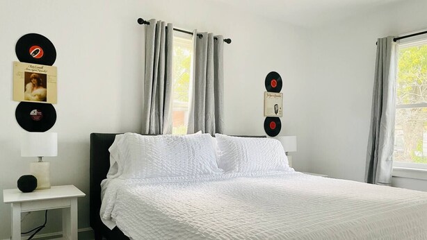 Un dormitorio con cama, una mesita de noche y tocadiscos fijados a la pared.