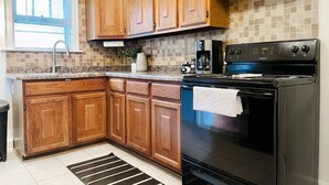 A kitchen with wooden cabinets, a black stove, and a tiled backsplash. - Cozy & Centrally Located APT - KING BED
 (Evansville)