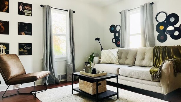 A living room with a sofa, armchair, coffee table, and wall art. - Cozy & Centrally Located APT - KING BED
 (Evansville)