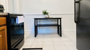 A kitchen with a black oven, a black table with a plant, and a black refrigerator. - Cozy & Centrally Located APT - KING BED
 (Evansville)