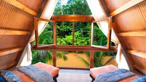 A room with a large open window, wooden beams, and two plush sofas. - Mont Carpe Diem (Bayamon)