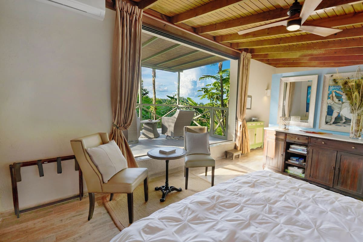 Une chambre à coucher comprenant un lit, un bureau, des chaises et donnant sur l’extérieur.