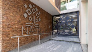 Una entrada moderna con pared de ladrillo, barandilla de metal y un portón decorativo.