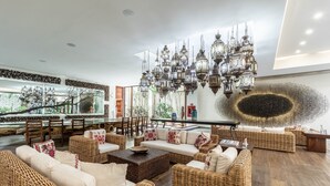 Un amplio salón con muebles de mimbre, una gran araña y vistas a una escalera.